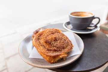 Warm cinnamon bun with icing sugar with cup of coffee