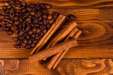 Pile of the coffee beans and cinnamon sticks on wooden table. Top view