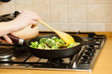 Woman cooking stir fry frozen vegetable on pan