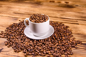White cup filled with coffee beans on wooden table