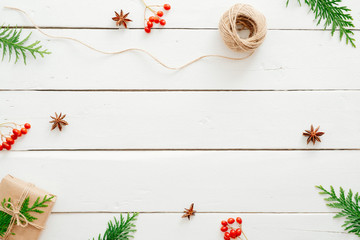 Christmas composition. Frame made of fir tree branches, red berry, presents on wooden white table. Christmas, winter holiday, New year concept. Postcard template mockup.