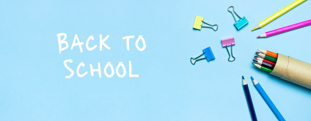 Back to school concept. Wooden colored pencils, paper clips on blue background top view flat lay copy space. Pencils for drawing, objects for creativity