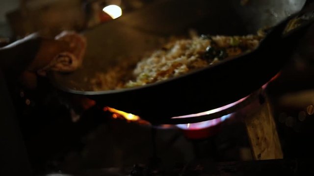 Shot of a street vendor cooking their indonesian food to sell by deep frying it in a bowl of cooking oil.  The meal is fried rice (Nasi Goreng) with egg and spices.