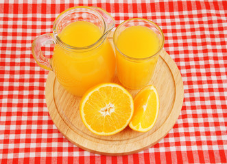 Orange juice in glass and pitcher on wooden board