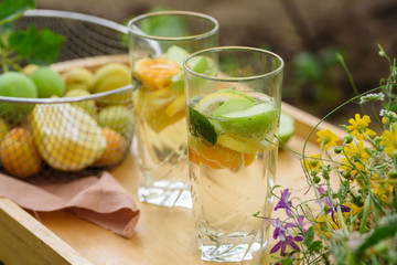 Summer lemonade with lemon, lime, ginger, with wildflowers on the table. Cooling drinks