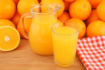 Pitcher and glass with orange fruit juice with oranges
