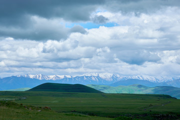 View of mountain snowy ridges on a bright sunny day with clouds in the sky.