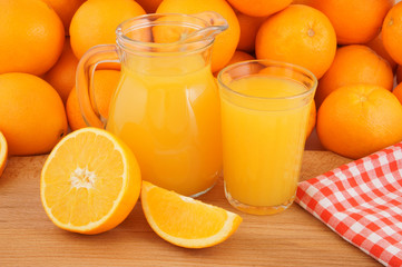 Orange juice in pitcher and glass with many orange fruits