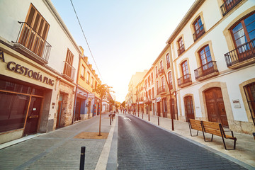 DENIA, SPAIN - JUNE 19, 2019: Calle La Mar street with old buildings and pavement at sunset.