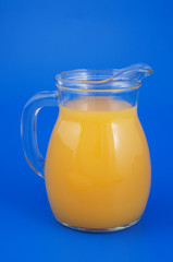 Orange juice in pitcher on blue background