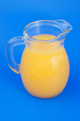 Orange juice in pitcher on blue background