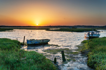 Summer sunrise over old boats on the shores of Holes Bay