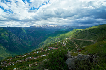 view of the village located in a mountain gorge on a bright sunny day with clouds in the sky.