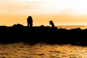 silhouette of couple on the beach during a photo shoot with a beautiful sunset in background.