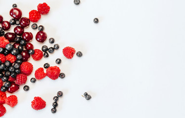  fresh raspberries, blueberries and cherries on a white background with a space for text