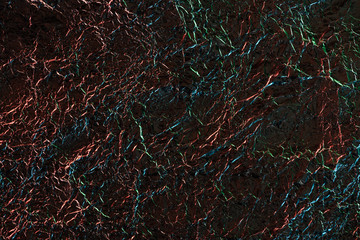 top view of silver crumpled foil with colorful lighting in dark