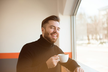 Attractive successful young businessman drinking coffee sitting at cafe table.