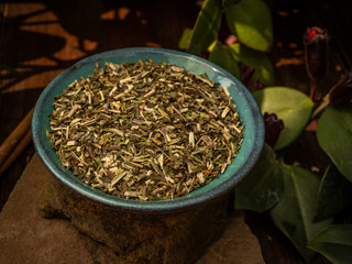 Shredded herbal tea. In a turquoise small plate on a stone. Cinnamon sticks