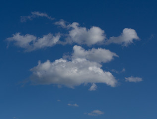 Naklejka na ściany i meble White fluffy clouds in the blue sky on a sunny day