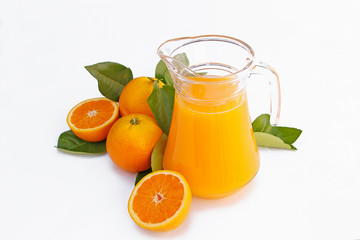 jug with fresh orange juice surrounded by ripe oranges