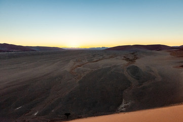 The rising sun illuminating the mighty dunes of the sossusvlei, as seen from dune 45, in Nambia.