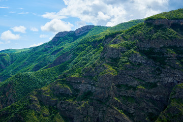 View of mountain snowy ridges on a bright sunny day with clouds in the sky.