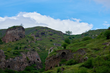 Cave city in the mountains on a sunny day with thunder clouds in the sky.