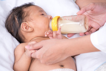 Obraz na płótnie Canvas Mother feeding newborn baby from milk bottle