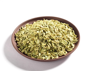 Fennel seeds (Foeniculum vulgare) in a clay plate on a white background