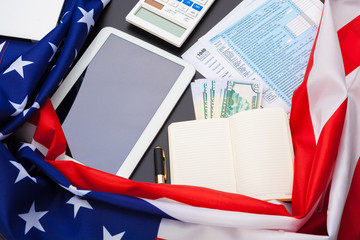 tax concept - 1040 tax form, pen, us money and flag