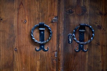 The entrance door to the ancient temple with a cross on the door and handles forged by a blacksmith.