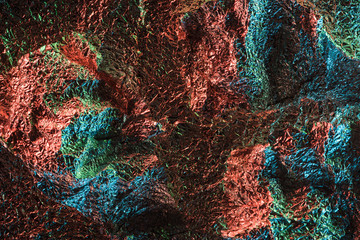 top view of glossy crumpled foil with colorful lighting reflection in dark