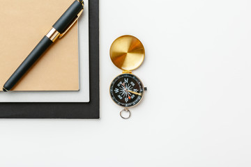 Black notepad for nautical notes and golden compass on a white table