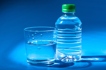 Glass of water with a bottle on table