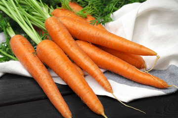 Bunch of fresh carrots with green leaves on wooden table