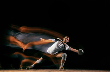 Caucasian young handball player in action and motion in mixed lights over black studio background....