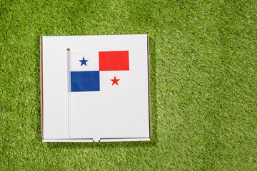 Paper box of pizza with Flag of Panama on the grass. Concept. Top view