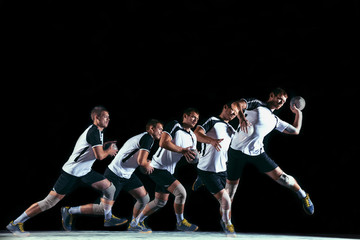 Caucasian young handball player in action and motion in mixed and strobe light on black studio...
