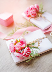 Composition with gift boxes decorated with green branch and rose.