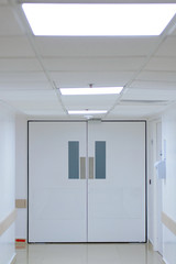 A huge white door in the white corridor in the hospital.
