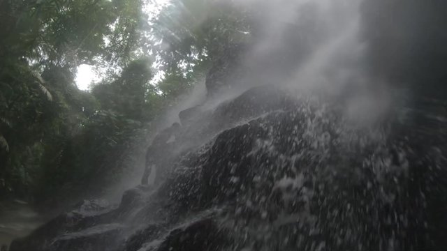A super slow motion shot of a waterfall in the jungle. Water drops fall slowly onto the camera. Filmed with action camera Gopro.