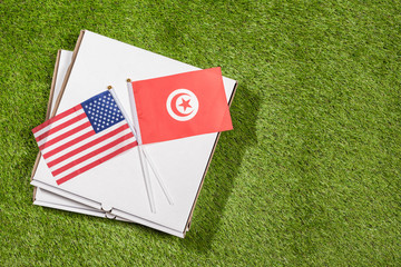 Paper box of pizza with flags of Tunisia and America on the grass. Concept of peace, partnership and friendship, . Top view