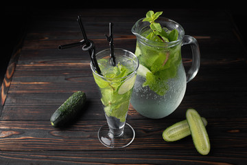 Lemonade a cucumber in a glass on a dark background