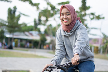 close up shot of hijab  woman in an outdoor hood with a bicycle posing in front of a camera on a bicycle