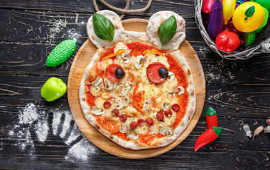 Baby pizza in the form of a bear with sausages, mushrooms and basil leaves