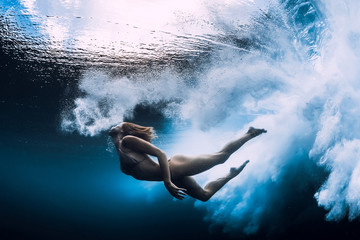 Obraz na płótnie Canvas Woman swim underwater with big ocean wave.