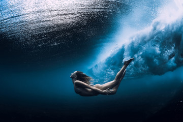 Woman swim underwater with ocean wave.