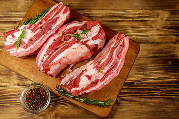 Raw pork ribs with spices and rosemary on wooden table. Top view
