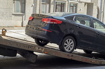 The car on a tow truck.Wrong parking on the street.