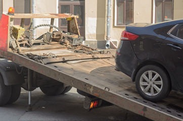 The car drives a tow truck.Wrong parking on the street.